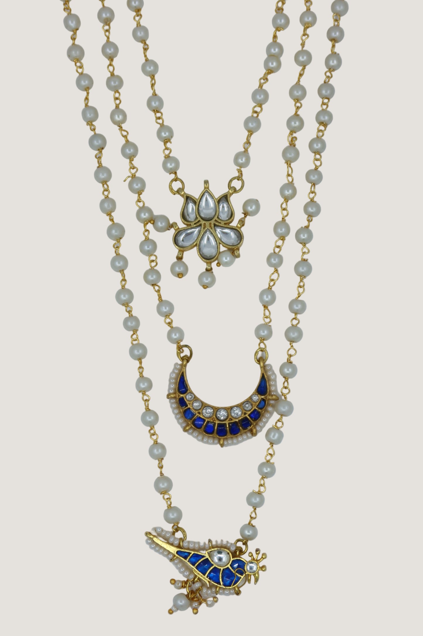 Gold necklace with decorative pendants on a light gray background