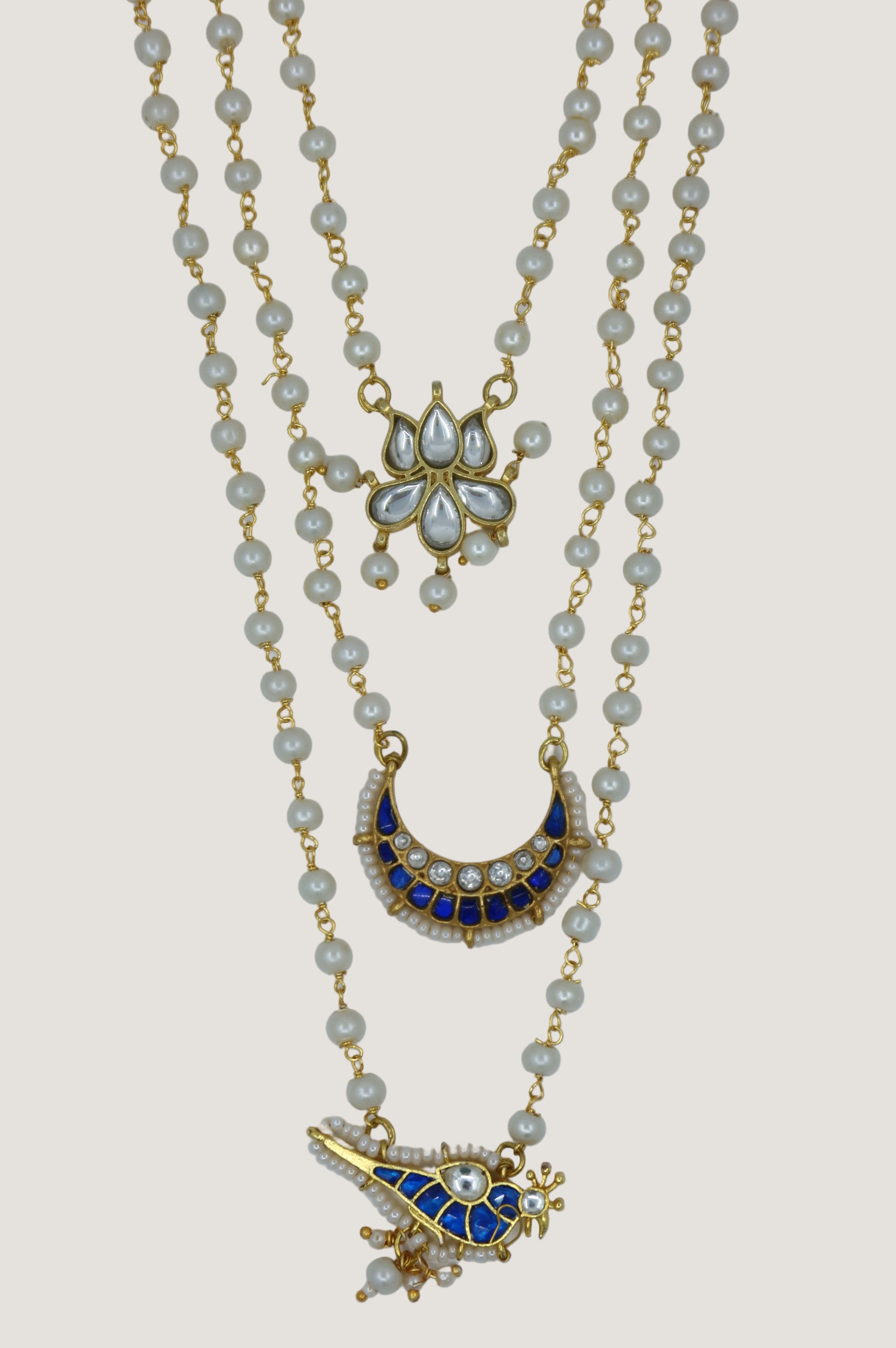 Gold necklace with decorative pendants on a light gray background
