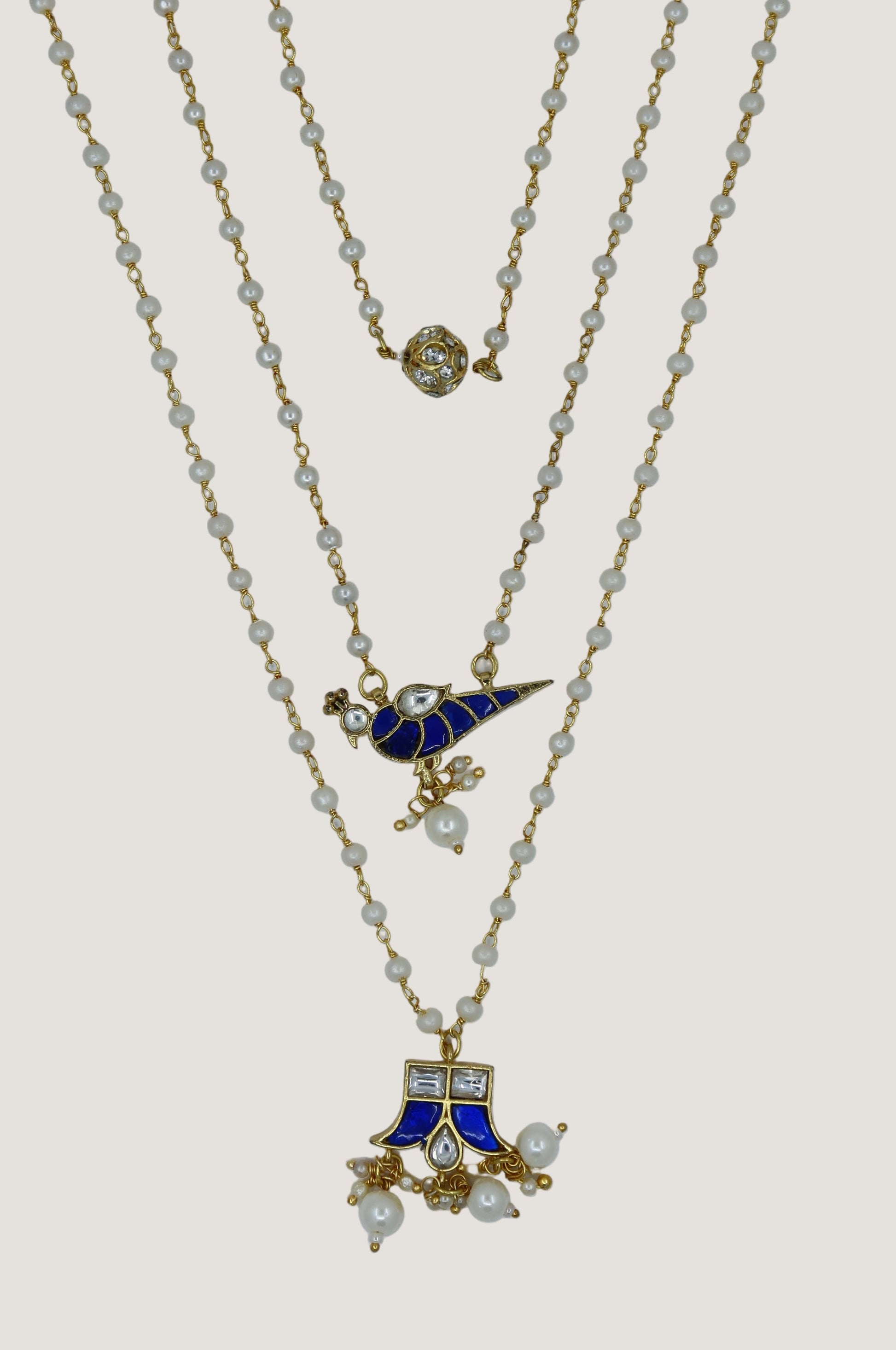 Three gold necklaces with blue and white pendants on a white background