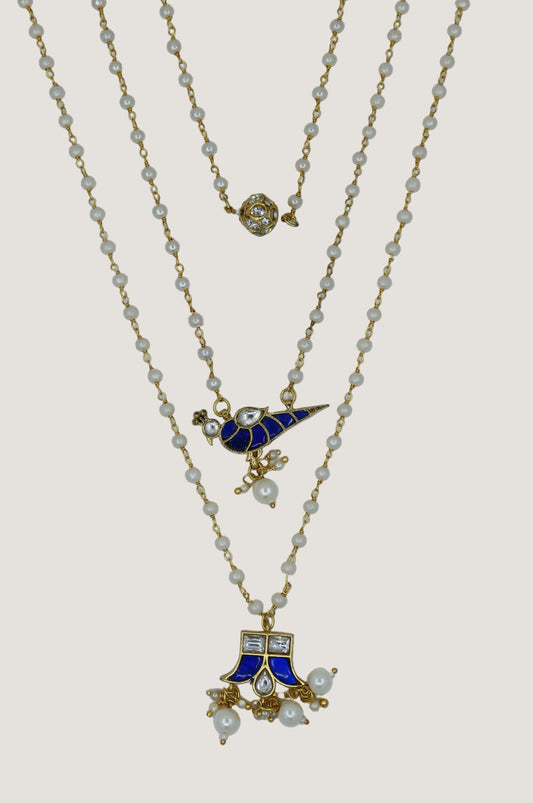 Three gold necklaces with blue and white pendants on a white background